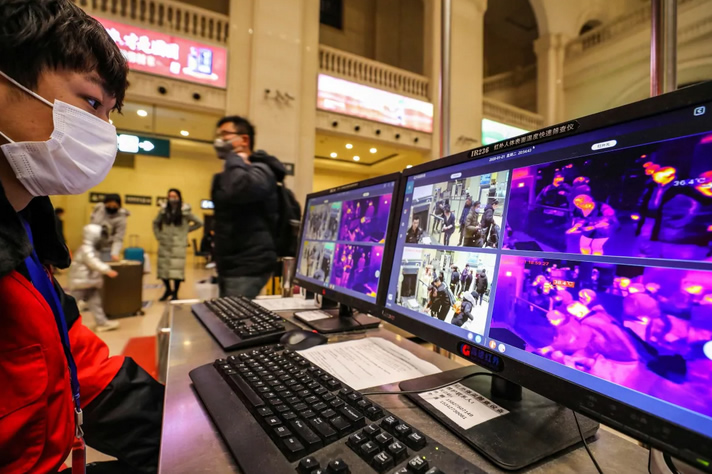 An image of a staff member that screens arriving passengers with thermal scanners at Hankou railway station in Wuhan, China.